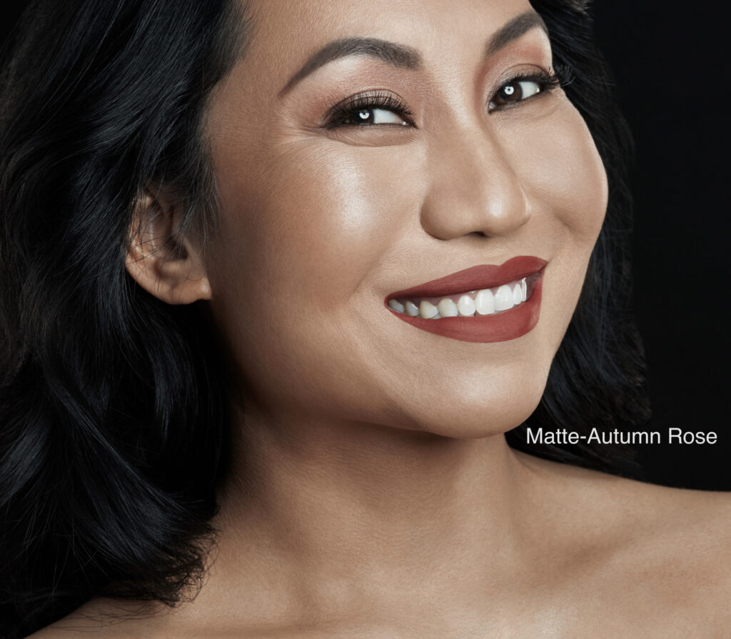 Close-up of a smiling woman with flawless makeup and smooth skin.