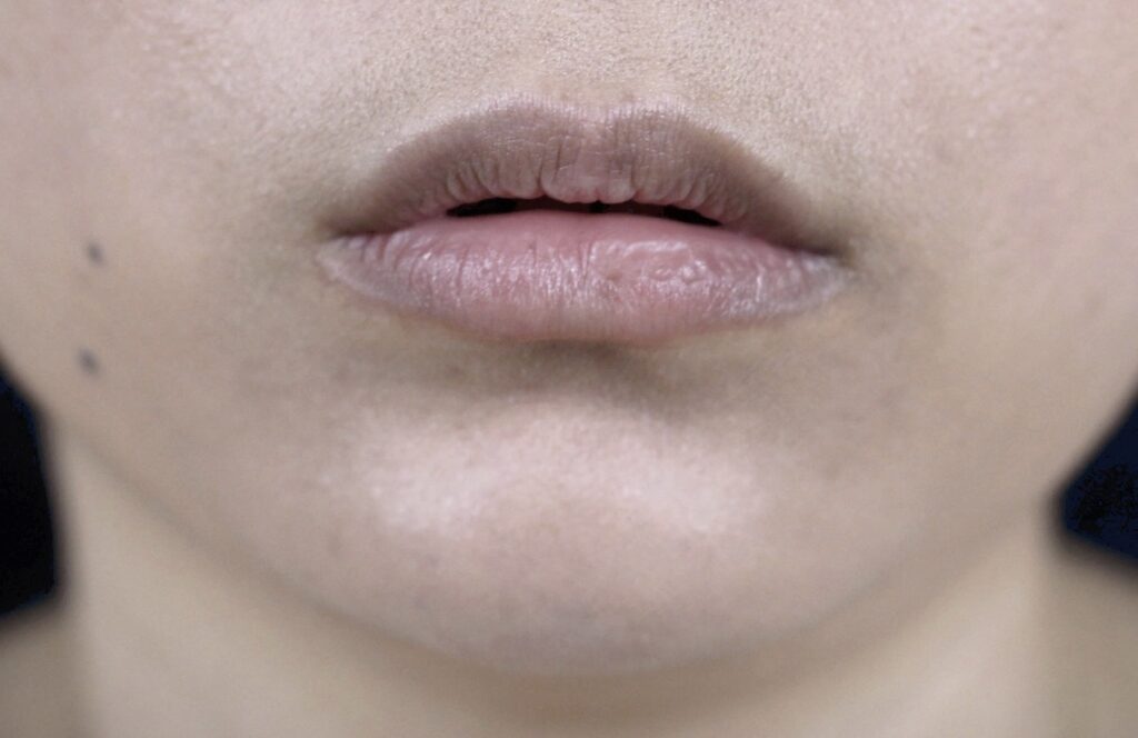 Close-up of slightly parted lips and chin with natural skin texture.