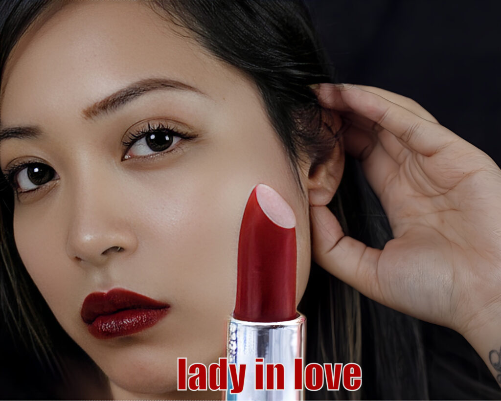 Close-up of a woman holding red lipstick near her face.