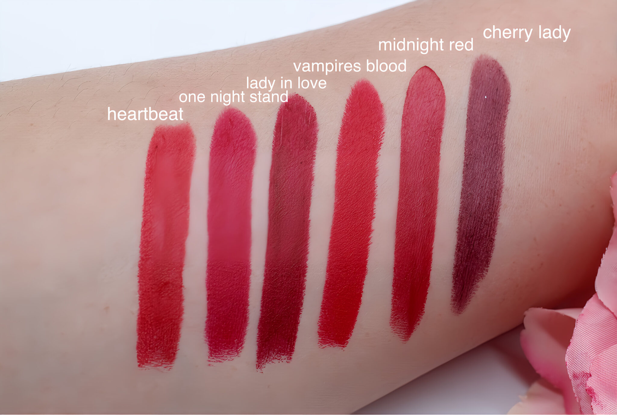 Swatches of red lipstick shades labeled on an arm.