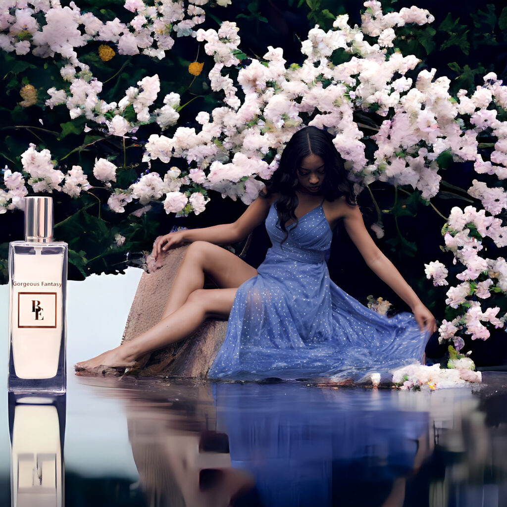 Woman in a blue dress sitting by a reflective water surface with blooming flowers.